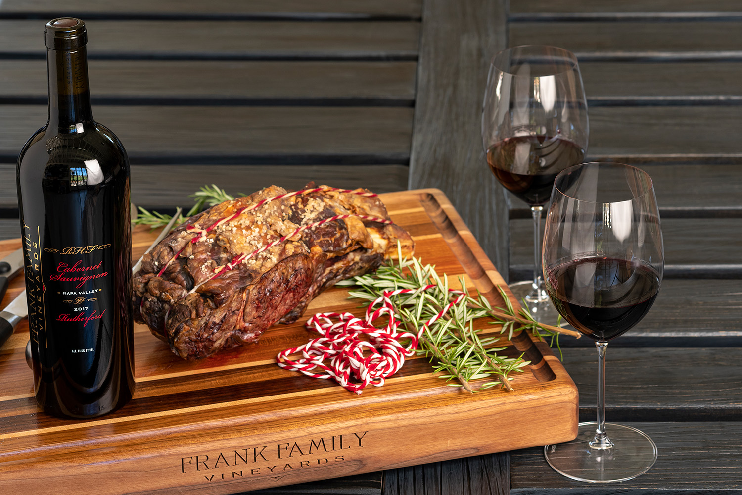 A bottle of Frank Family's RHF Cabernet Sauvignon next to a rib roast and two wine glasses
