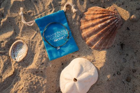 A custom 4ocean bracelet on top of a blue bag on the beach