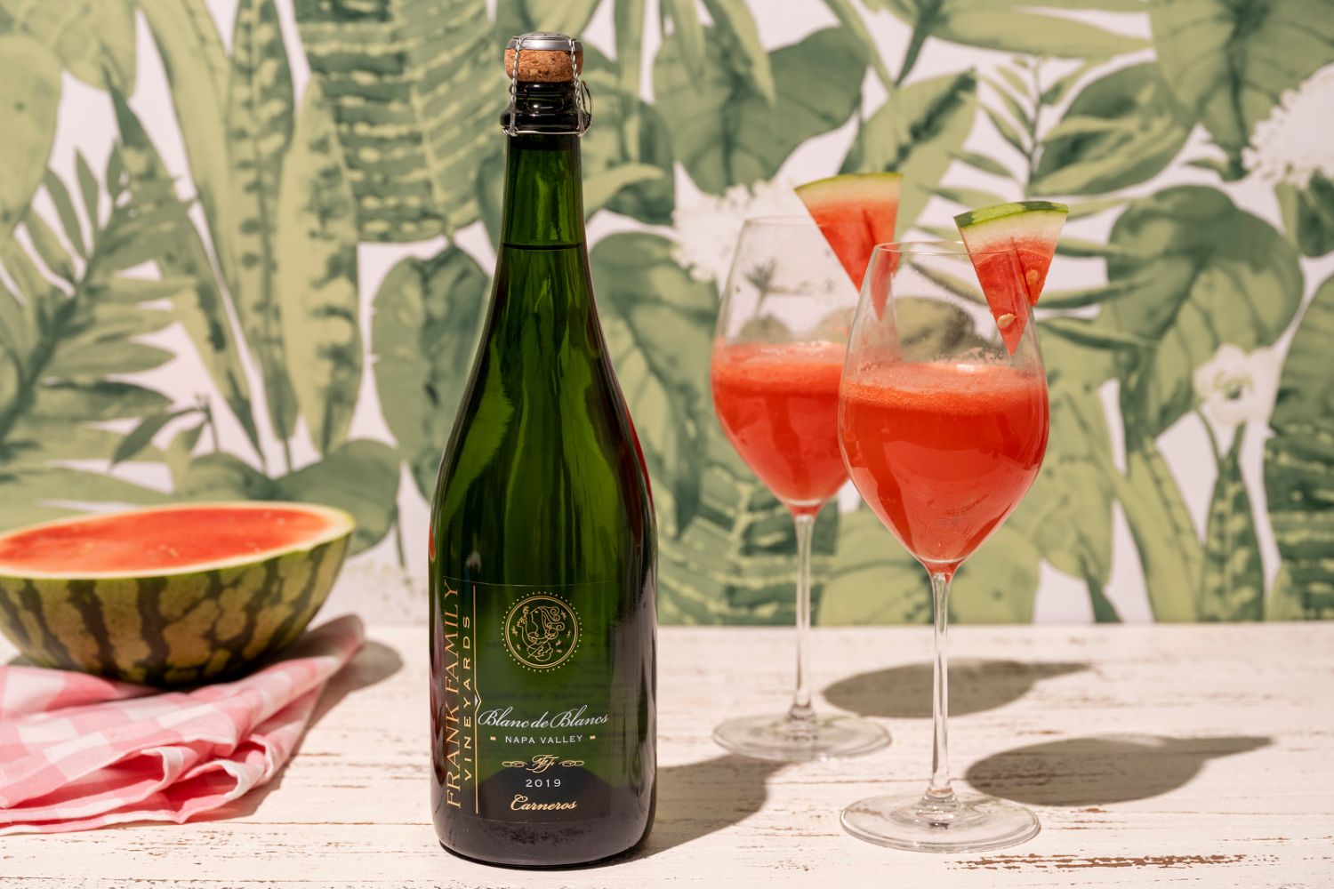 Two glasses of colorful pink cocktail garnished with watermelon triangles