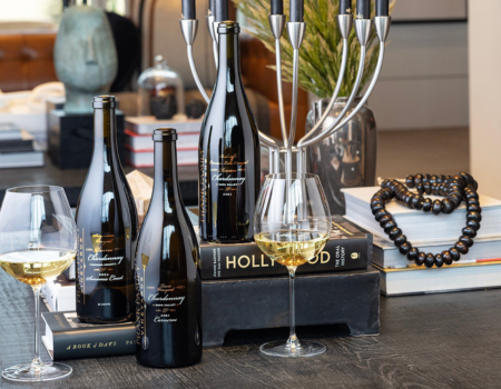 Bottles of Frank Family's Sangiacomo, Lewis, and Beckstoffer Vineyard Chardonnays among a stack of Hollywood themed books. 